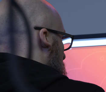 Mann sitter foran røde skjermer på et datarom