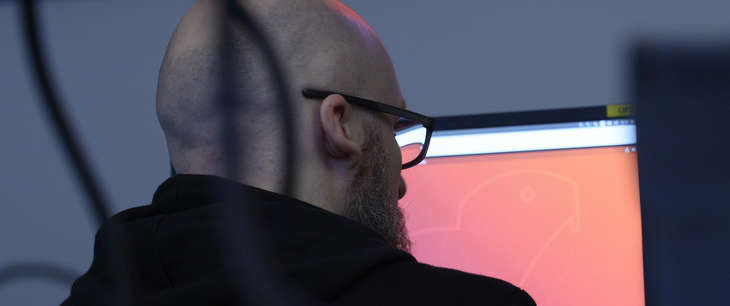 Mann sitter foran røde skjermer på et datarom