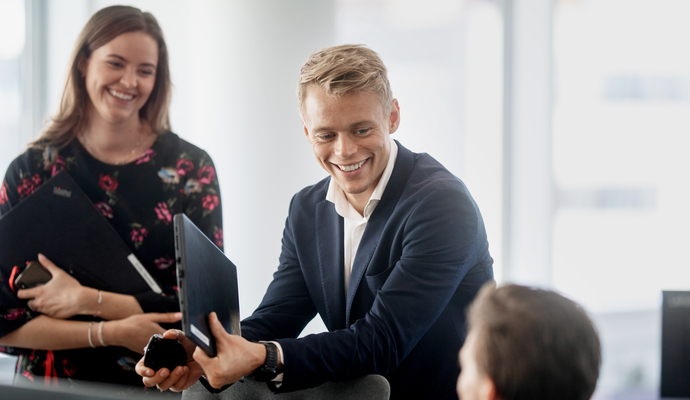 Tre smilende personer som snakker sammen