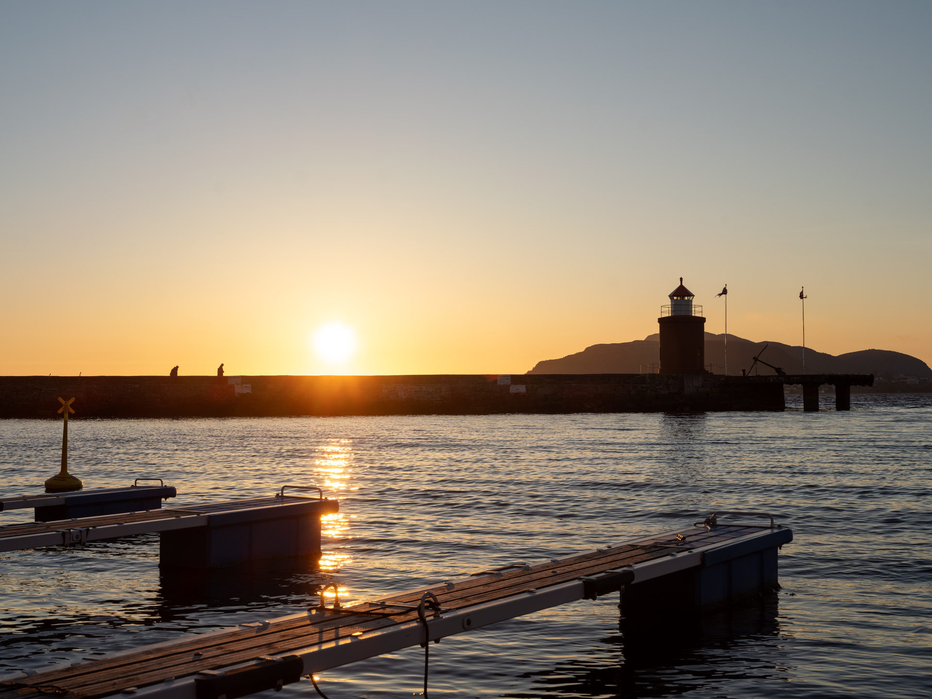 Solnedgang i Ålesund havn med vakker natur og rolig sjø. 