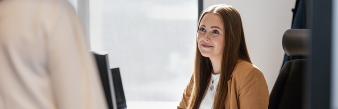 Kvinne sittende i stol i dialog med en annen person