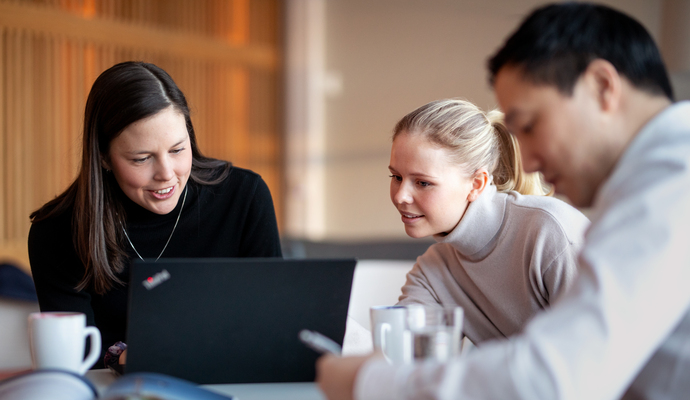 3 personer foran en laptop